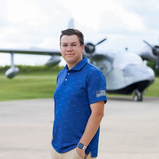model wearing polo in front of airplane 