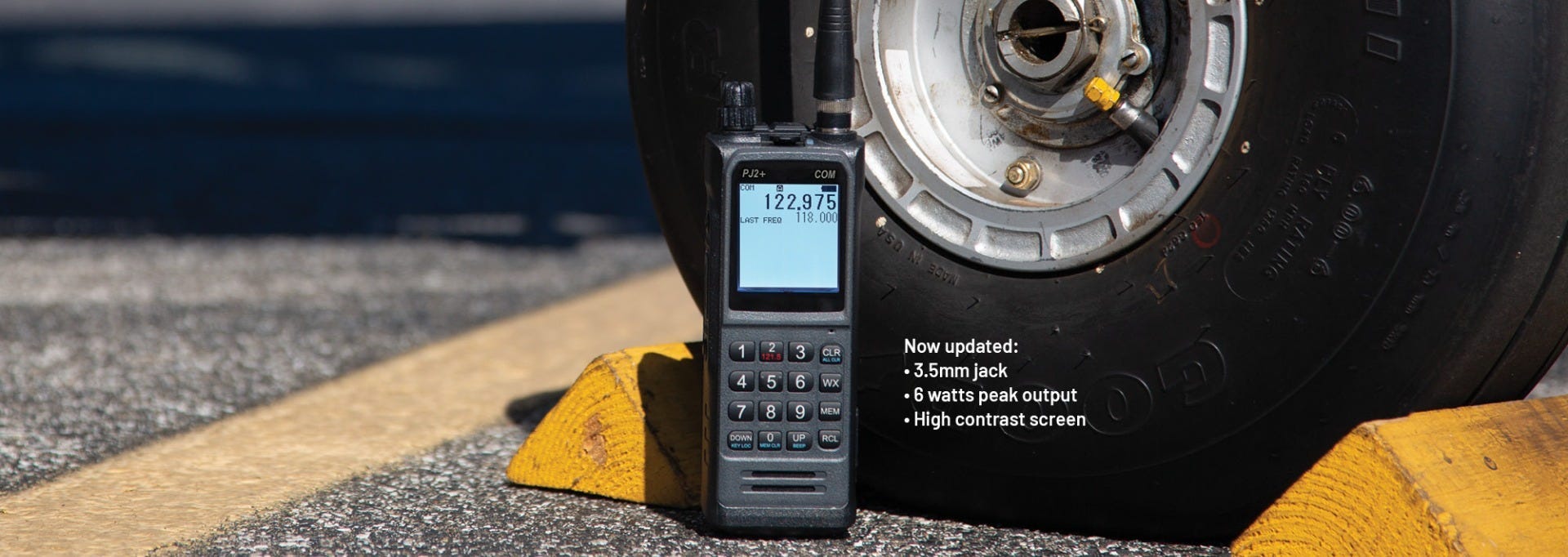 PJ2+ COM Radio displayed next to wheel of parked plane